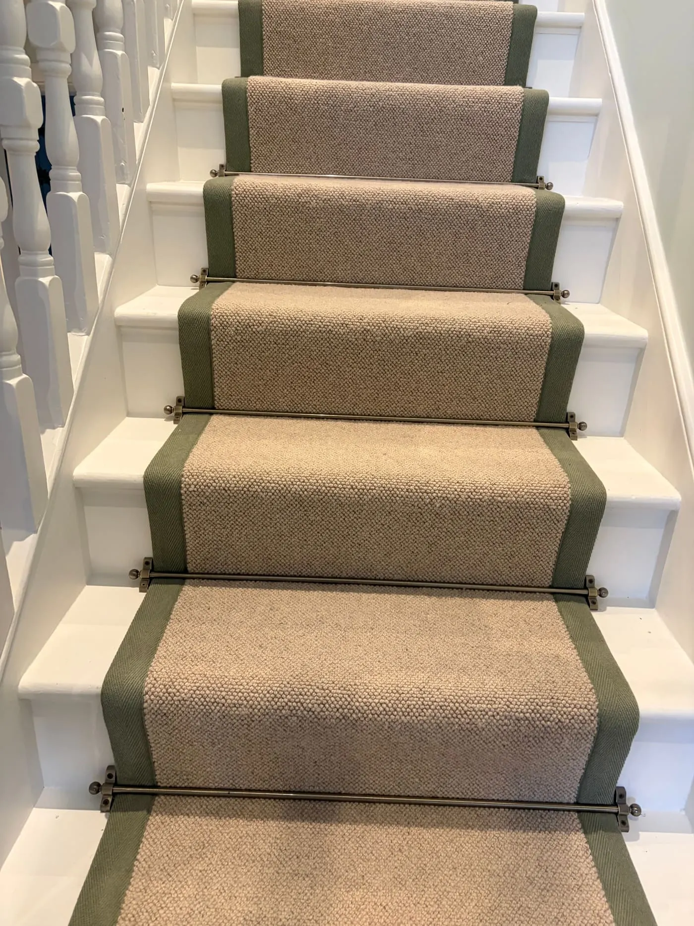 Beige stair runner with a sage green border on a white staircase