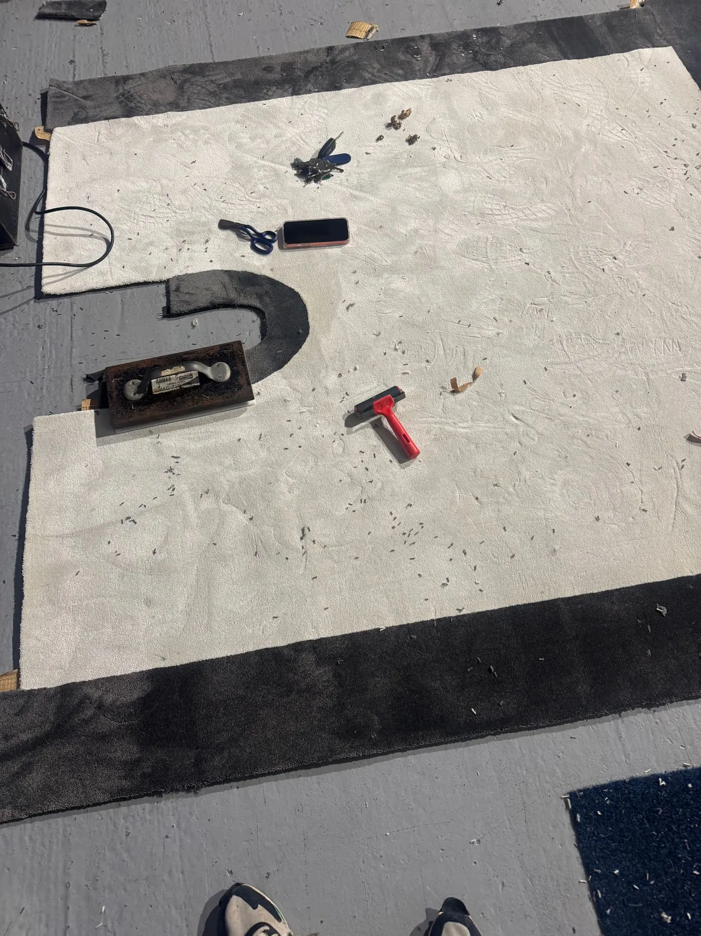 Cream carpet with a black border being fitted, tools still on the floor