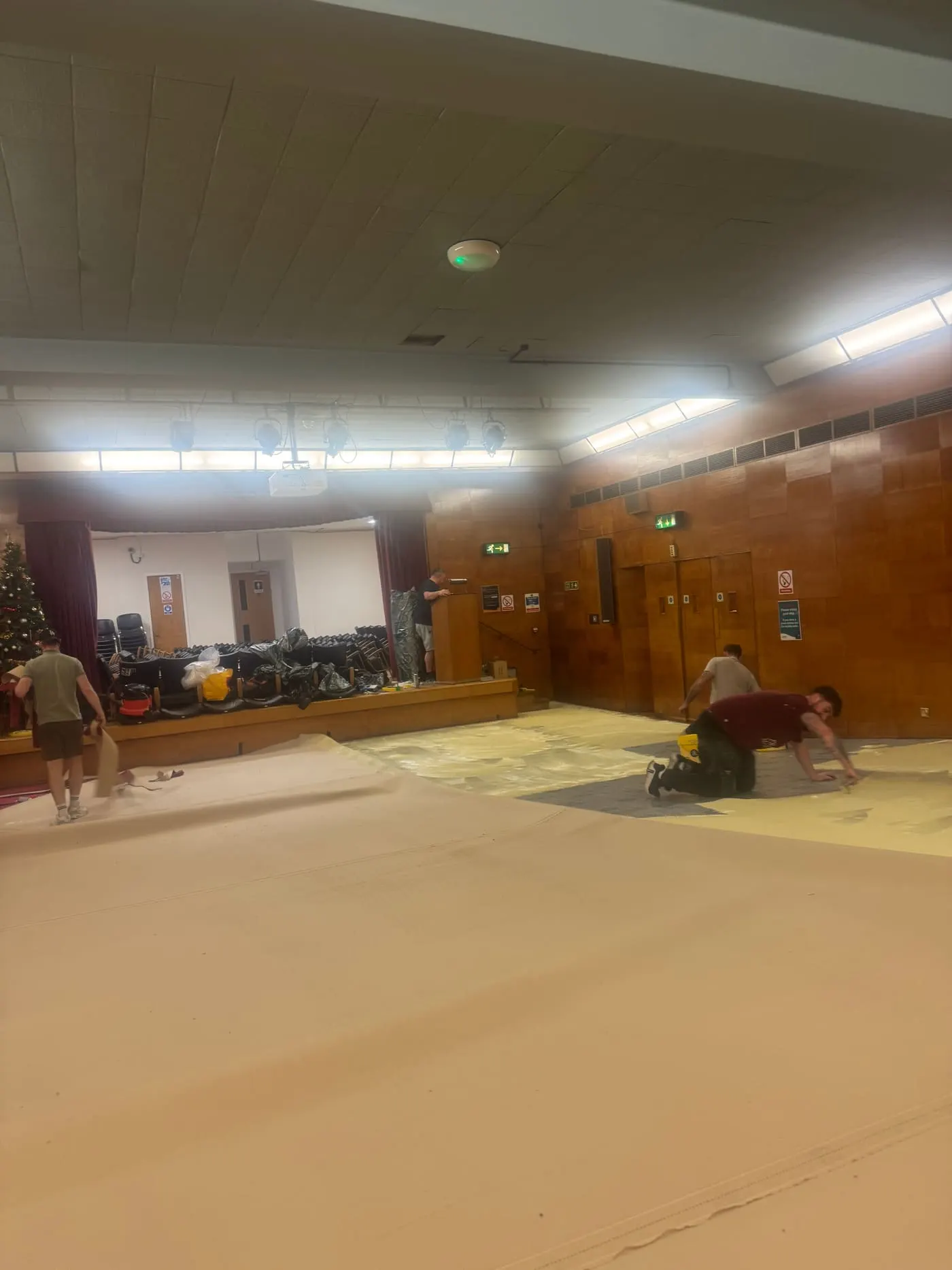Large cream carpet being fitted in a wood-panelled function hall