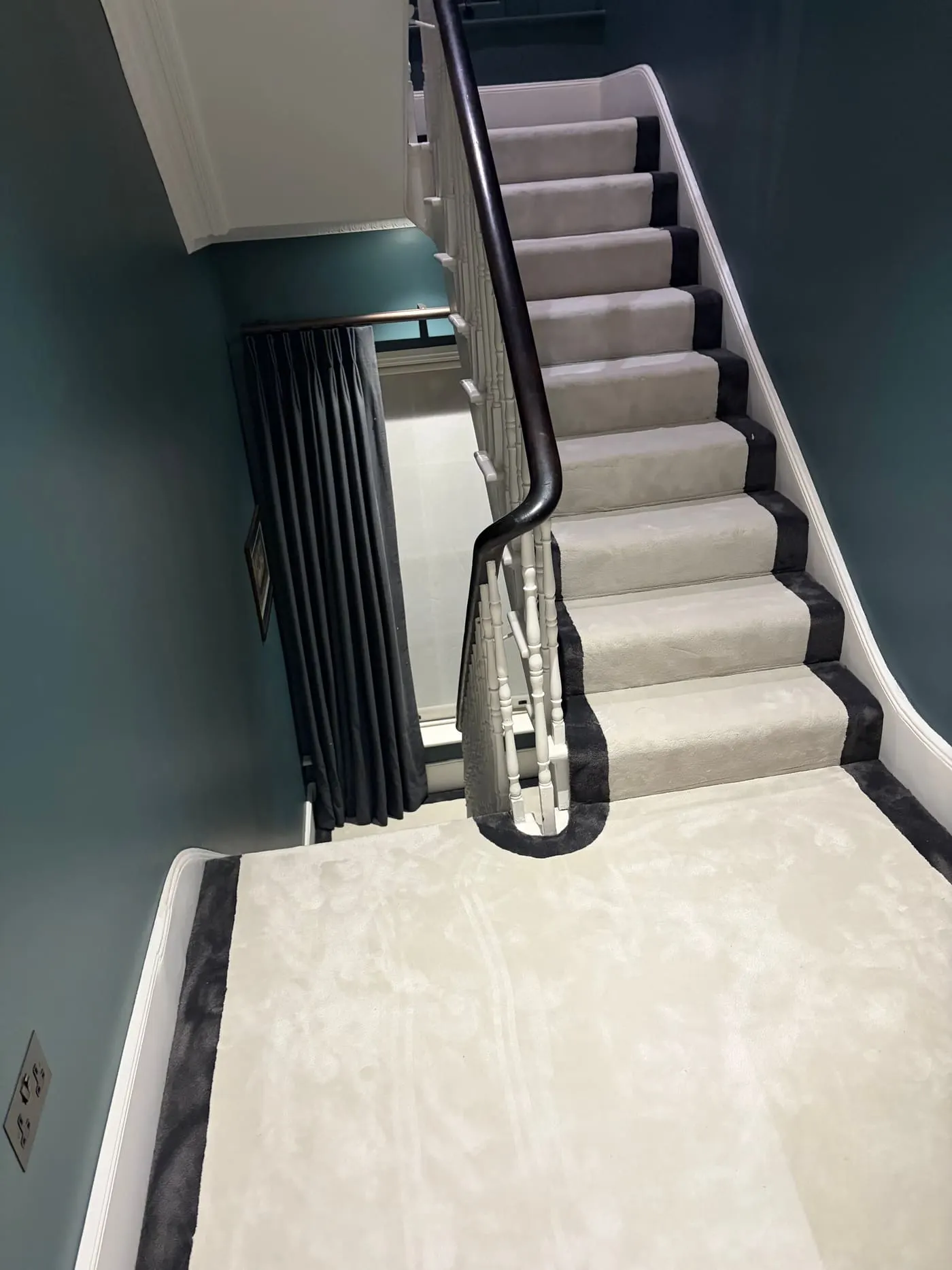 Cream stair runner with black border on a curved staircase with black handrail