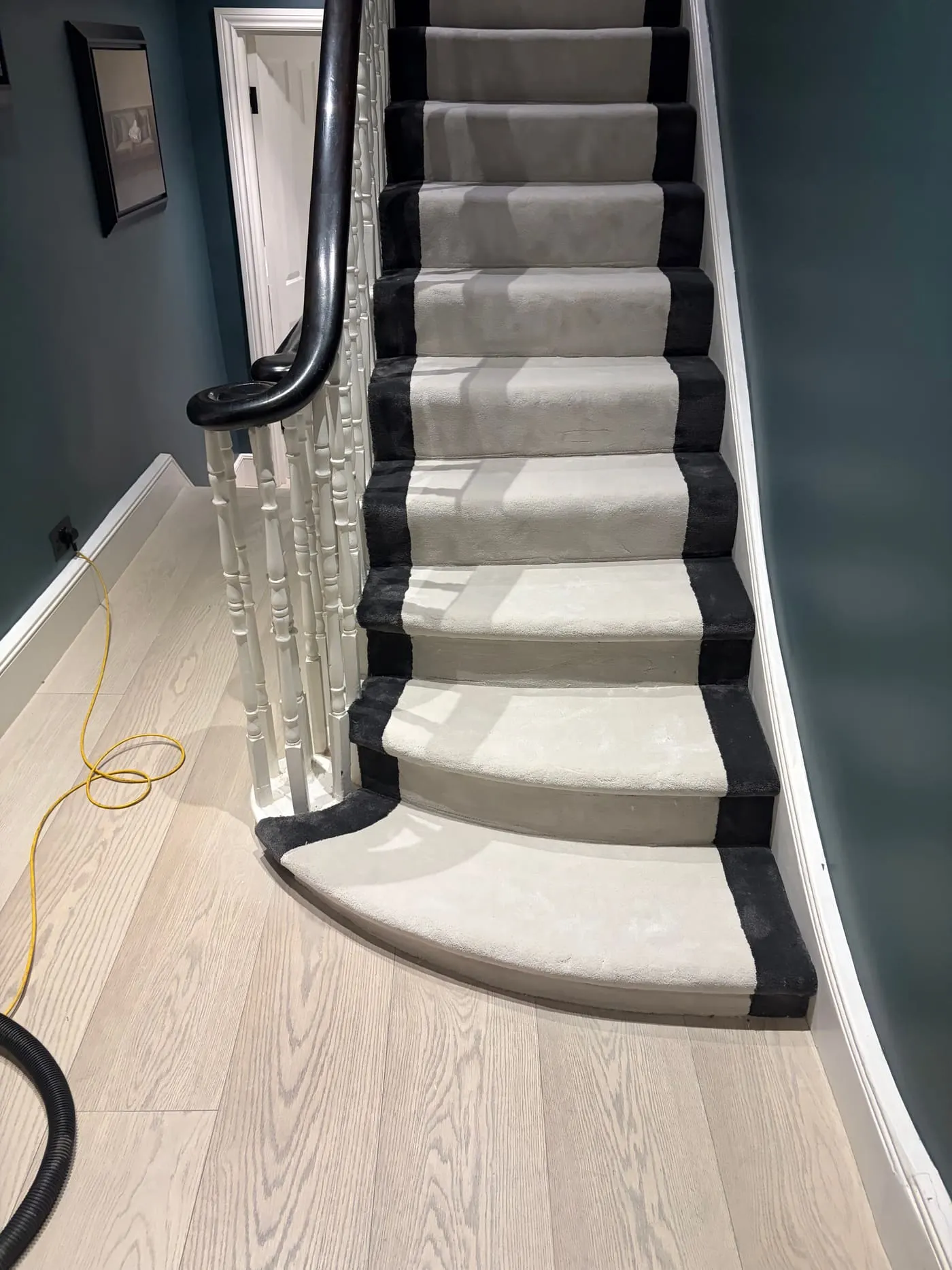 Cream stair runner with black border turning a corner on a winding staircase