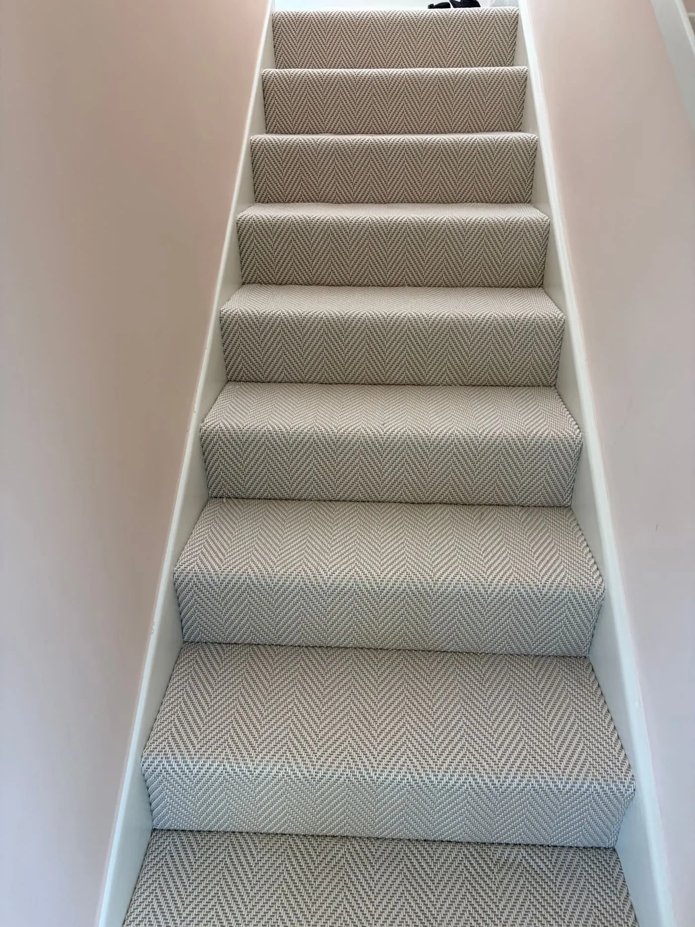 Grey herringbone-pattern carpet fitted on a straight staircase