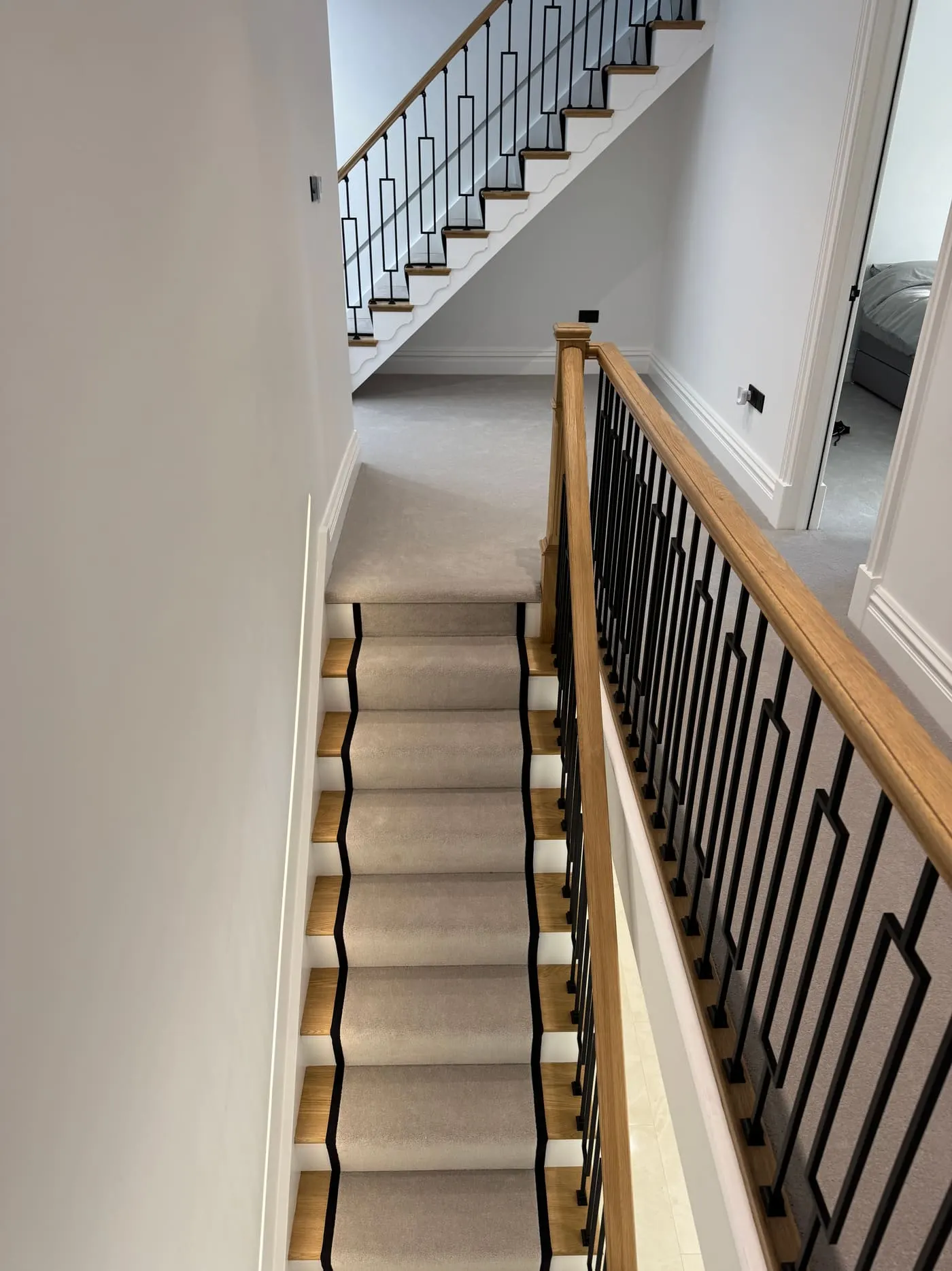 Grey stair runner with black border on an oak staircase with black balustrade