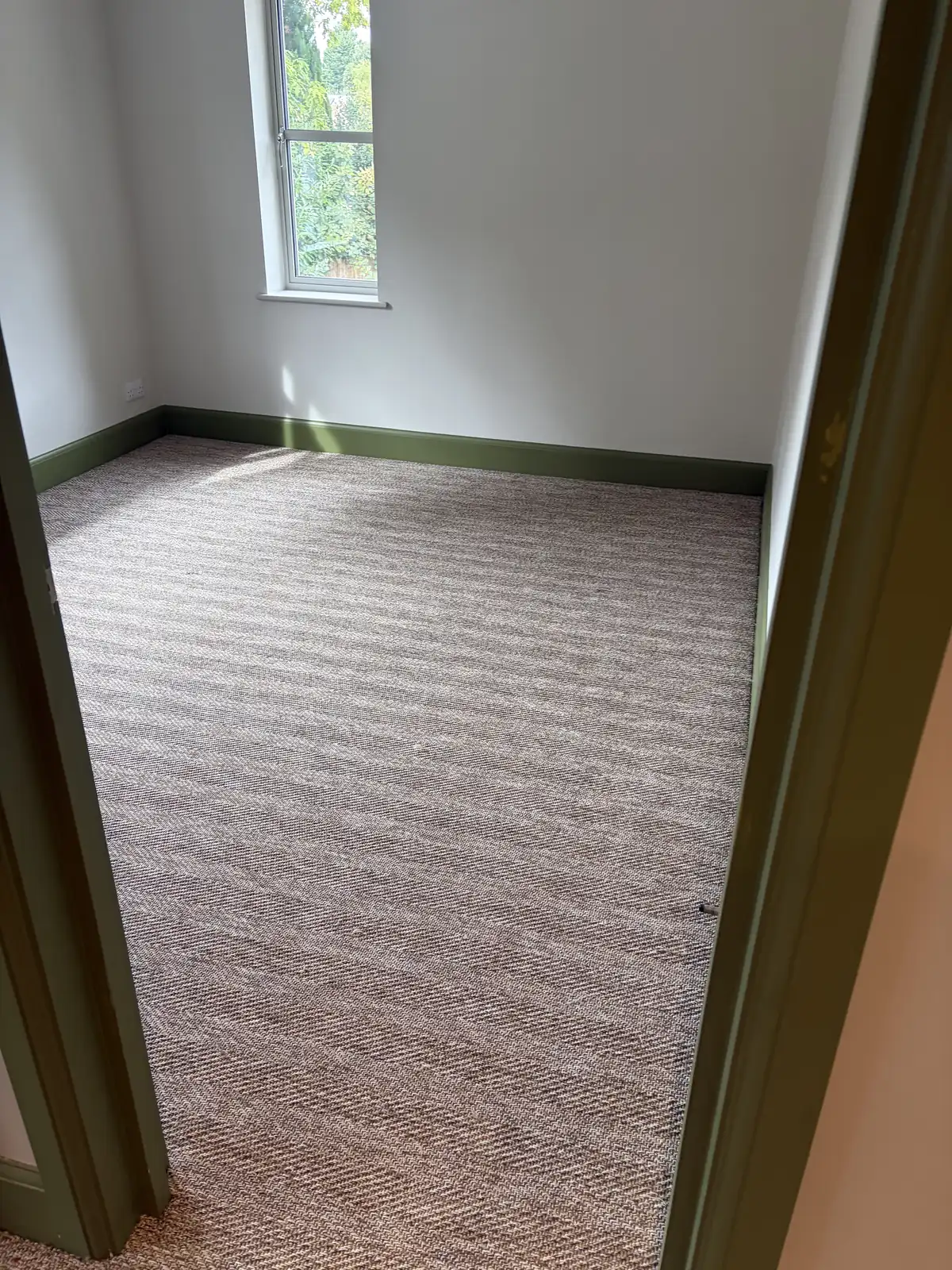 Grey striped carpet newly fitted in a bright empty room