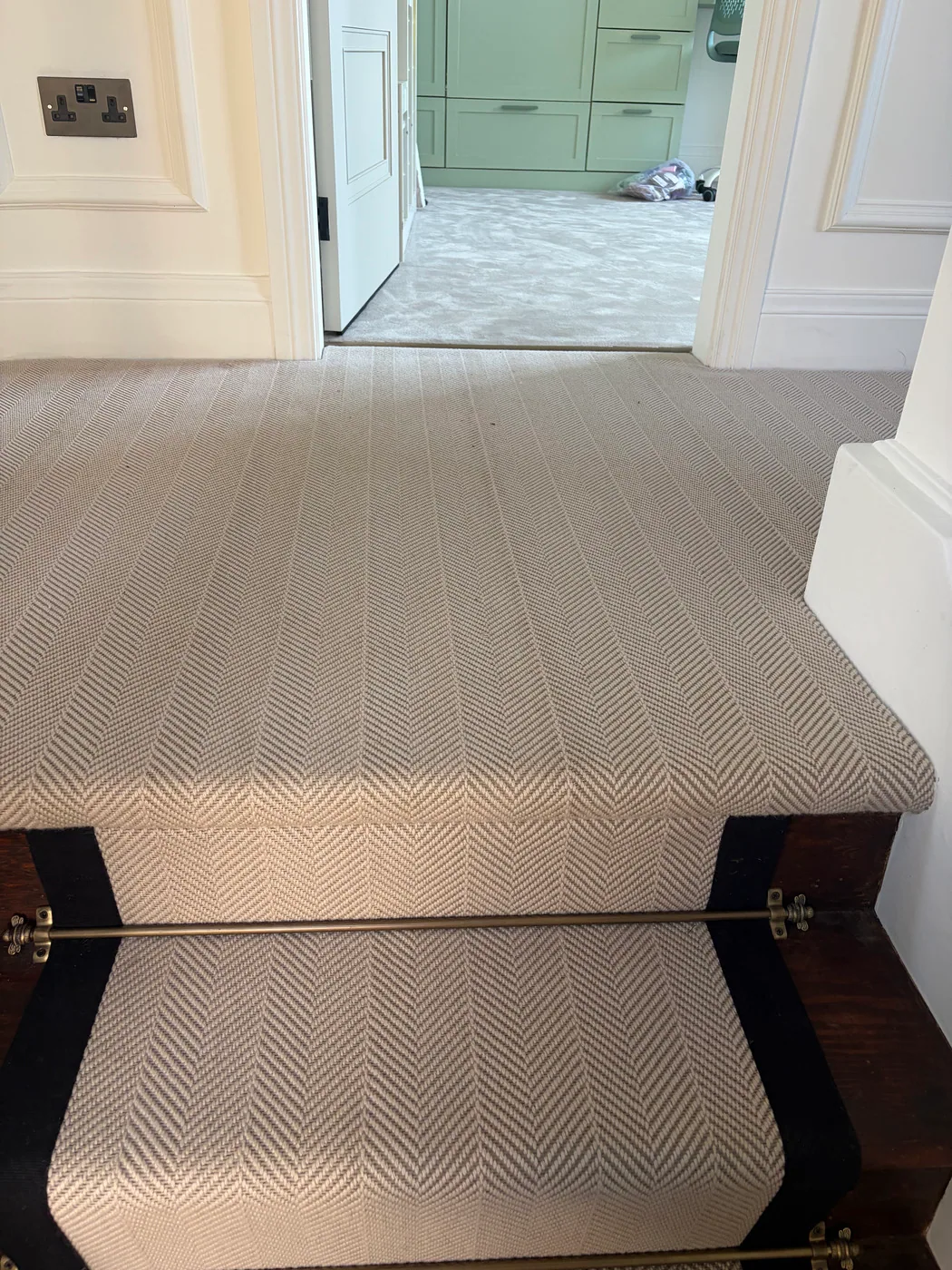 Herringbone stair runner with black border continued neatly across a landing