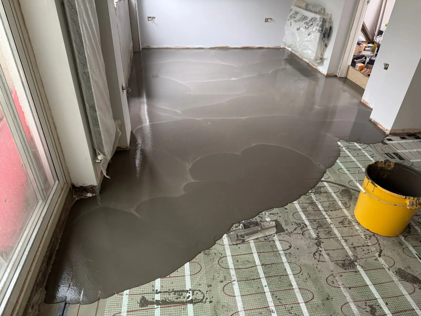 Liquid screed poured over underfloor heating pipes before flooring
