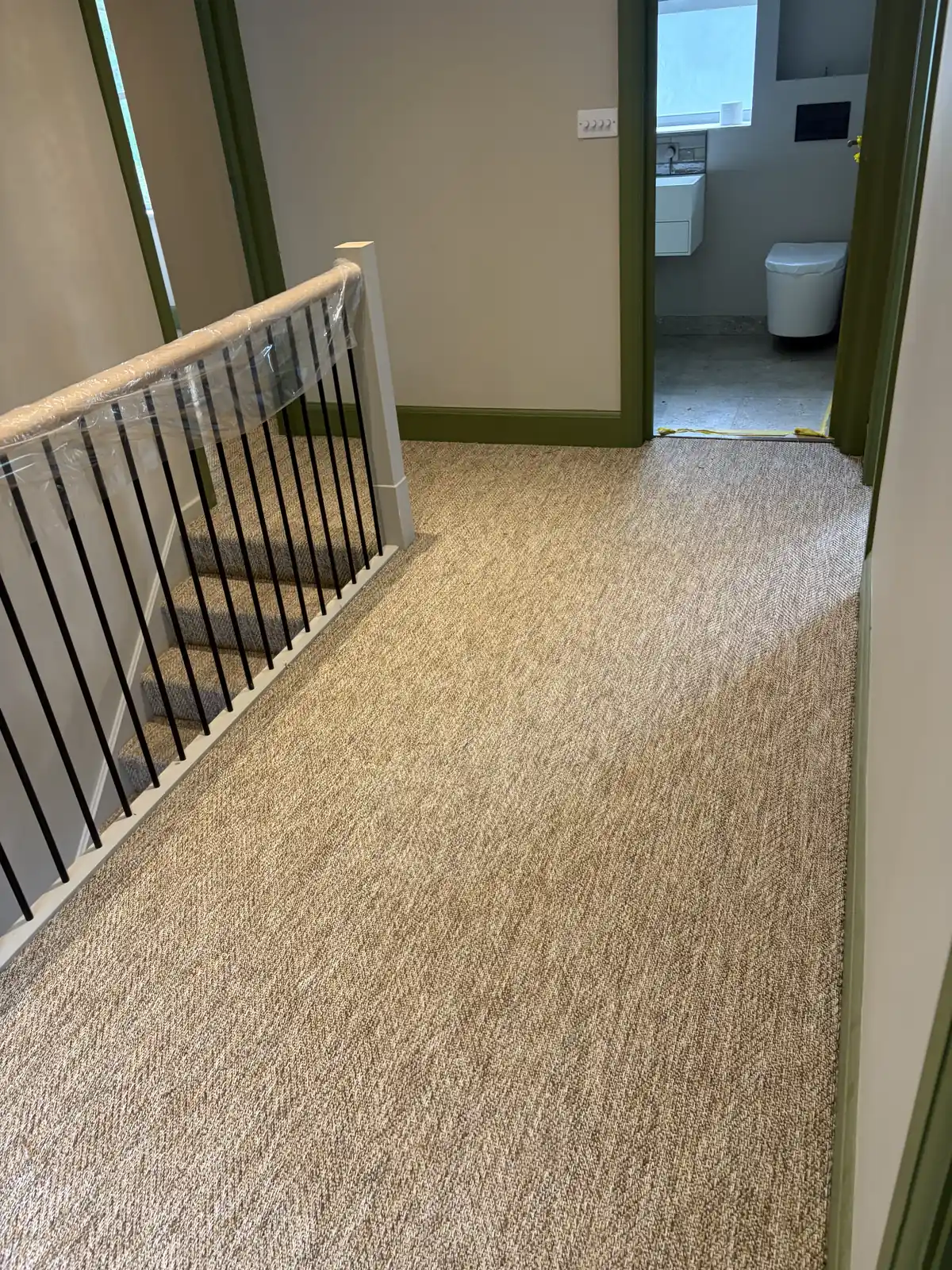 Natural loop carpet fitted across an upstairs landing beside the staircase