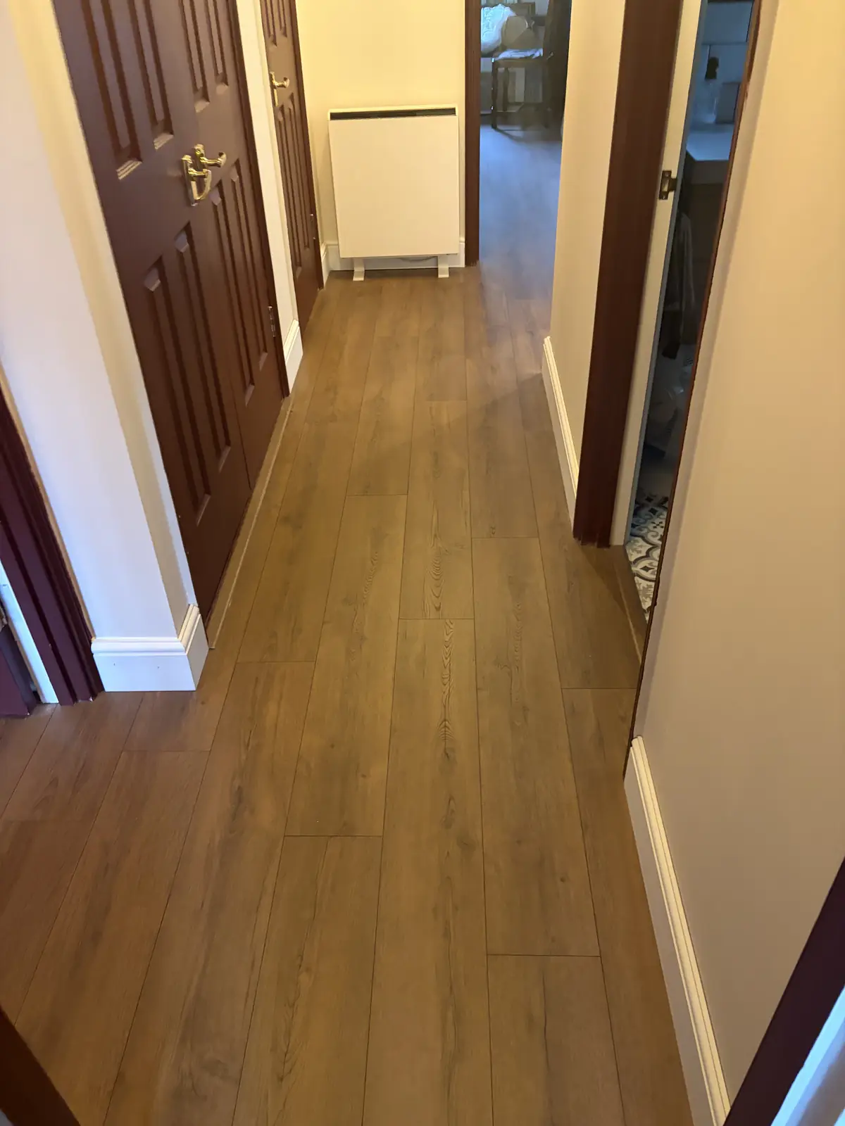 Oak-effect laminate flooring installed along a narrow hallway