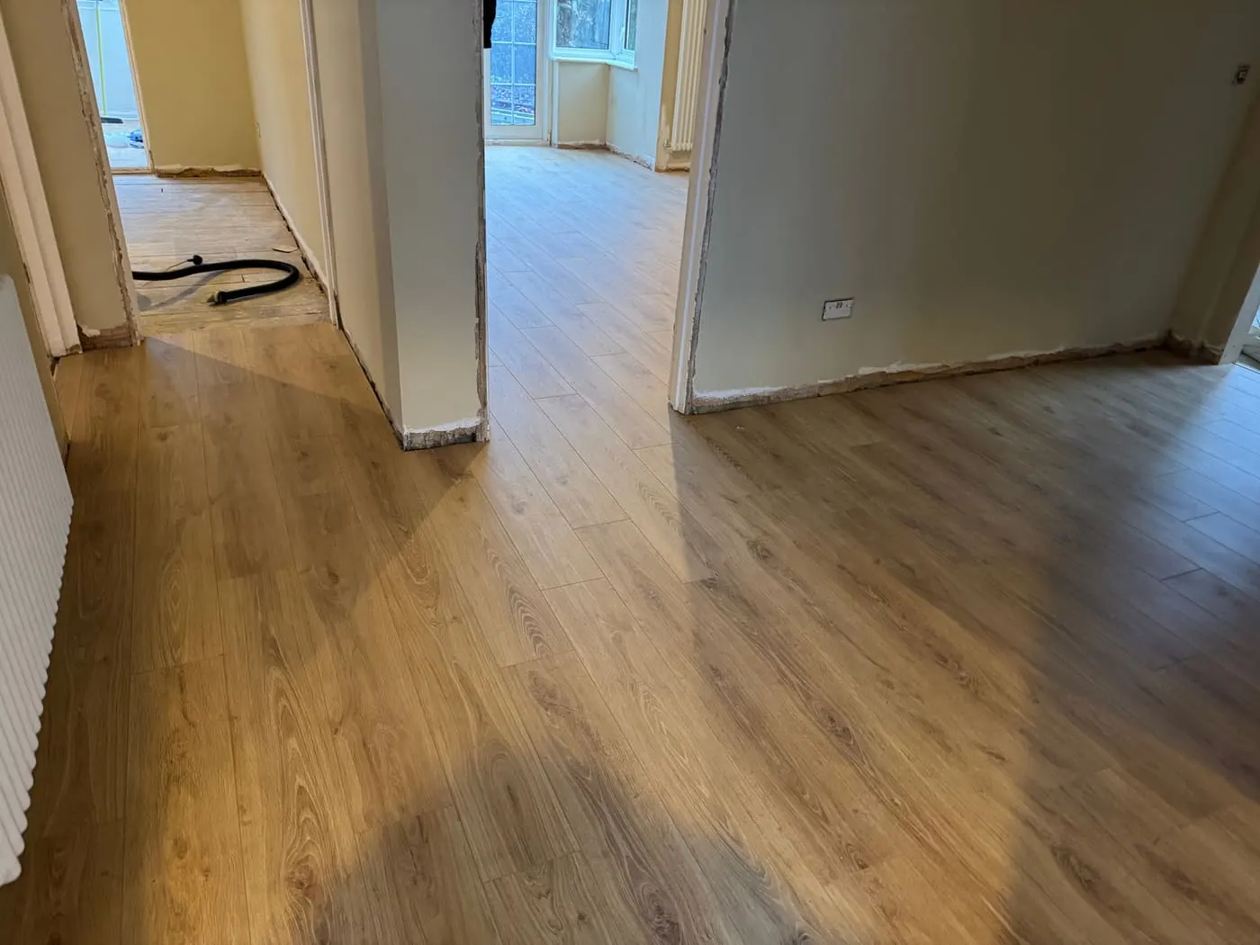 Oak-effect plank flooring fitted through a doorway between two rooms