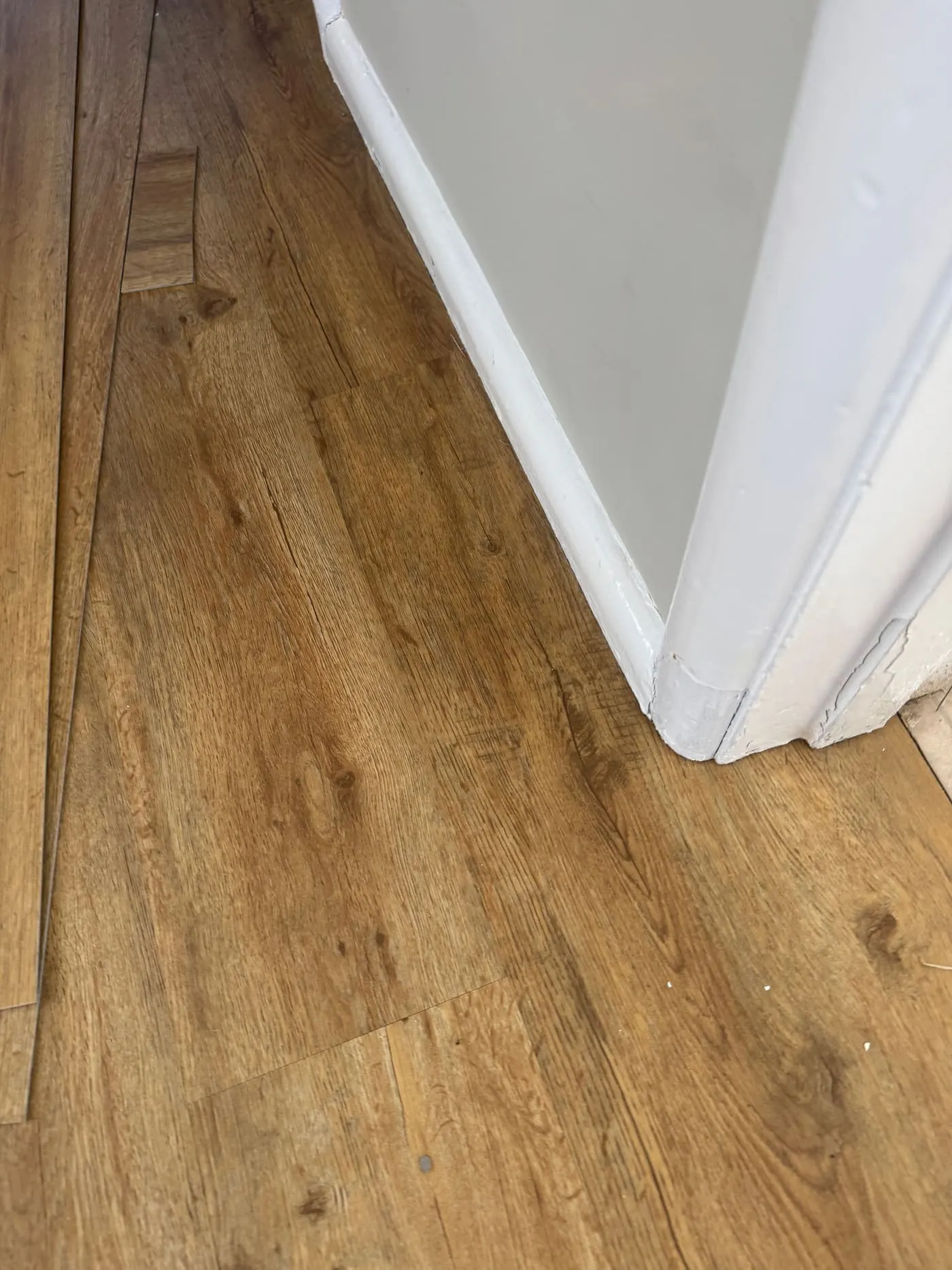Close-up of oak-effect plank flooring fitted neatly against white skirting