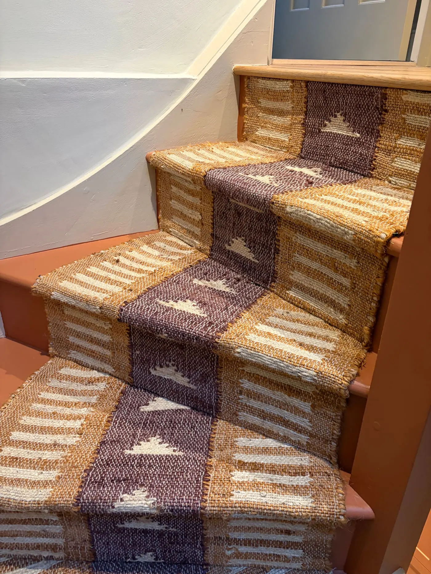 Patterned purple and cream stair runner fitted on a curved staircase